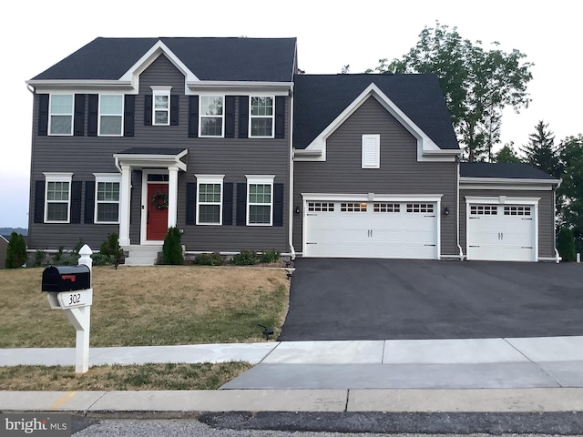 colonial inspired home featuring a garage and a front yard