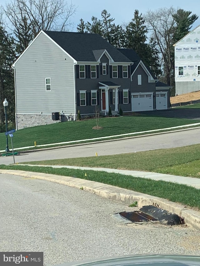 view of front of property with a garage, cooling unit, and a front yard