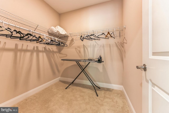 walk in closet with light colored carpet