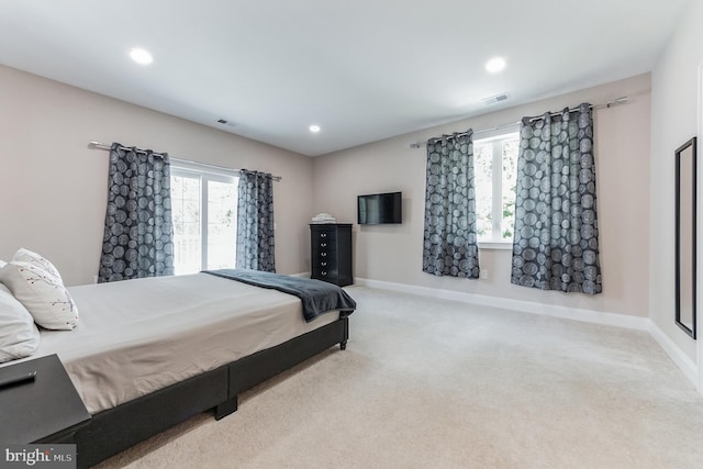 bedroom with light carpet and multiple windows