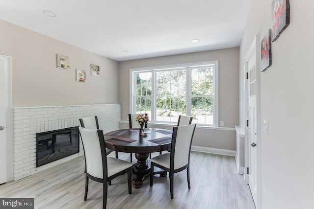 dining room with a brick fireplace and light hardwood / wood-style flooring