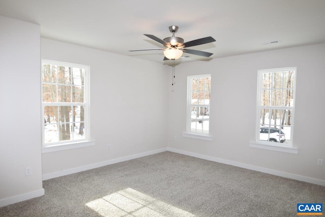 carpeted spare room with a wealth of natural light and ceiling fan