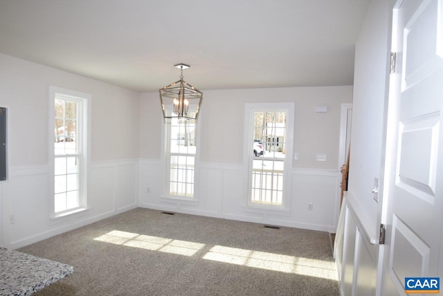 unfurnished dining area with light carpet and a notable chandelier