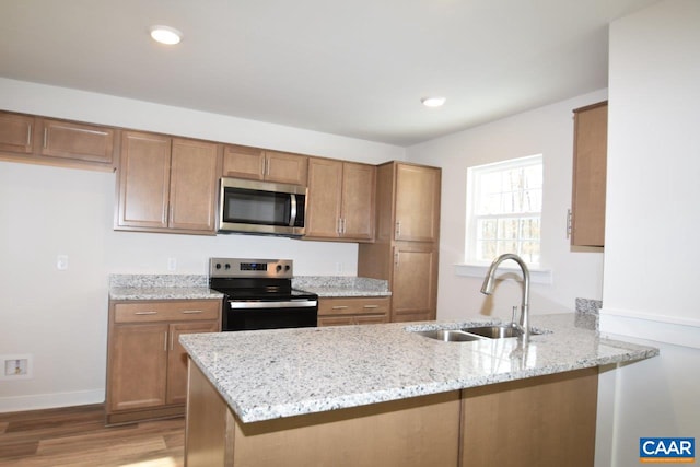 kitchen with light stone counters, appliances with stainless steel finishes, kitchen peninsula, and sink