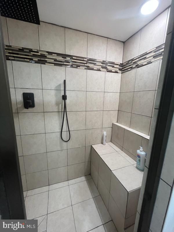 bathroom with a tile shower and tile patterned flooring