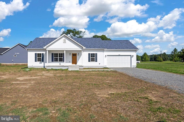 view of front of house featuring covered porch, a garage, and a front lawn