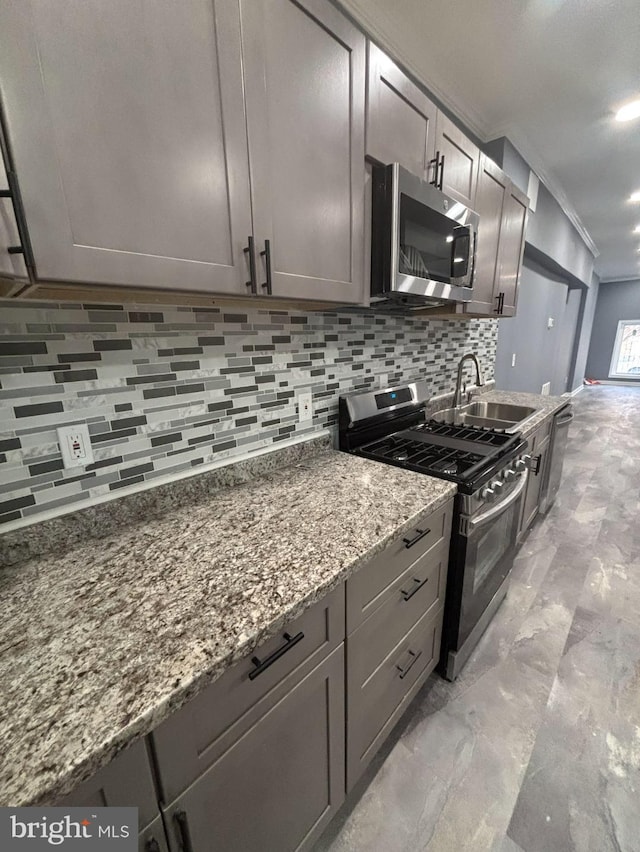 kitchen with stone counters, crown molding, sink, appliances with stainless steel finishes, and tasteful backsplash