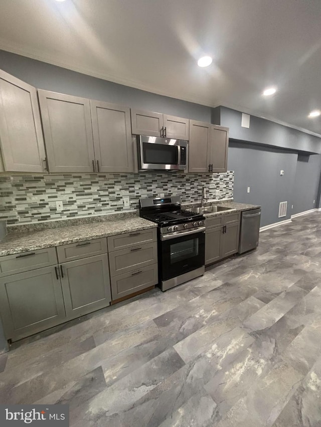 kitchen featuring decorative backsplash, sink, light stone countertops, and stainless steel appliances