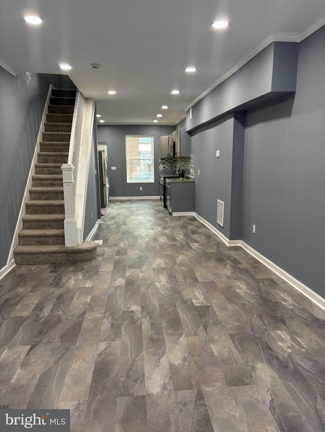 basement with stainless steel refrigerator and crown molding