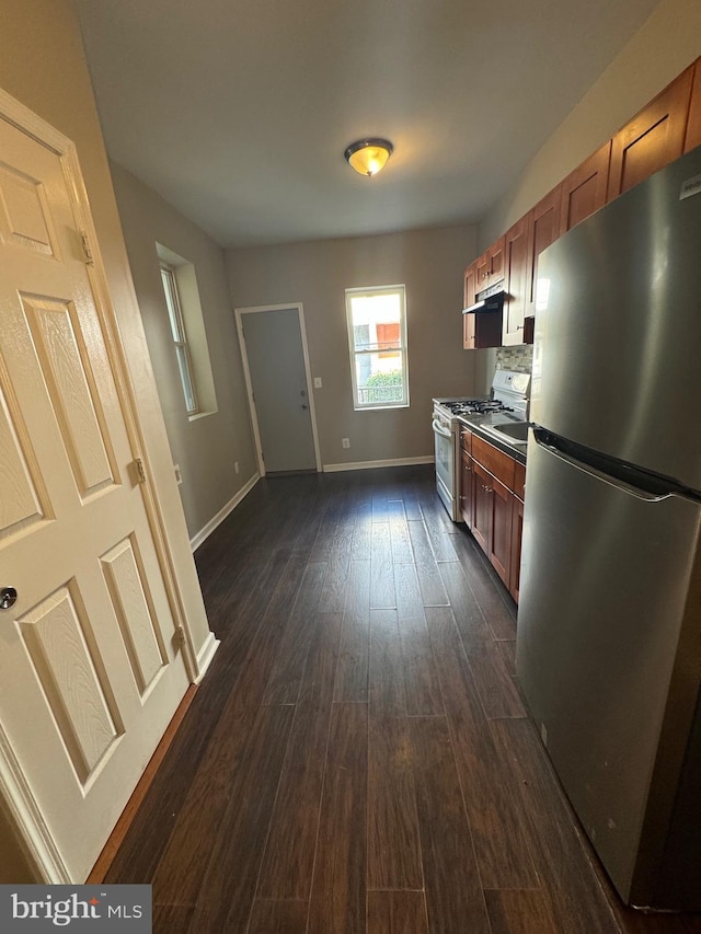 kitchen with decorative backsplash, dark hardwood / wood-style flooring, stainless steel refrigerator, and white gas range oven