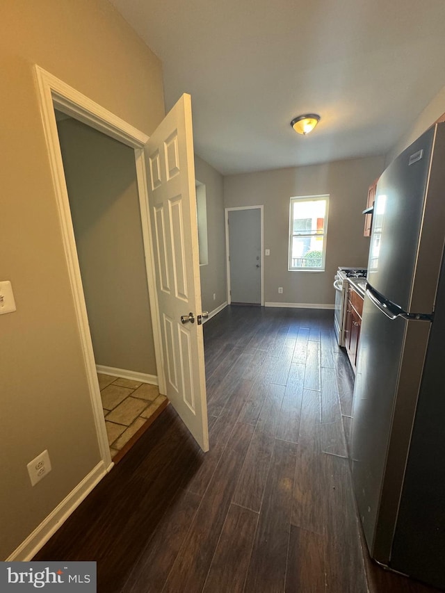 interior space with white gas stove, dark wood-type flooring, and stainless steel fridge