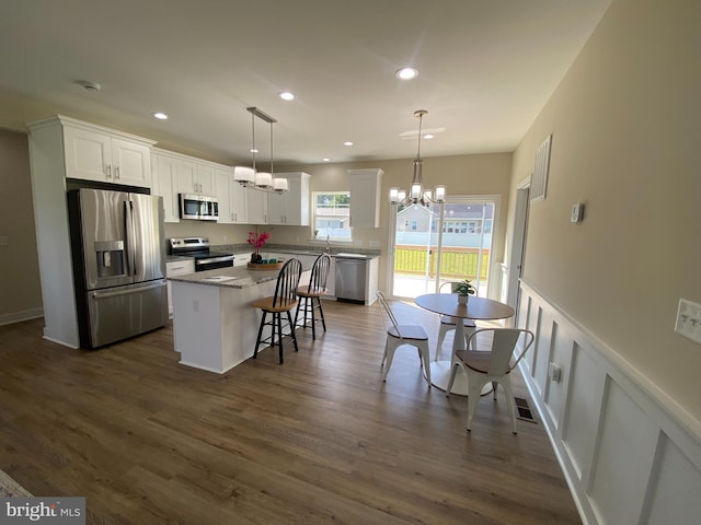 kitchen featuring pendant lighting, a center island, white cabinets, appliances with stainless steel finishes, and stone countertops