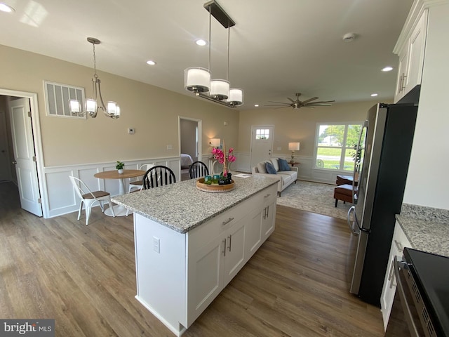 kitchen featuring stainless steel fridge, ceiling fan with notable chandelier, white cabinetry, and light stone counters