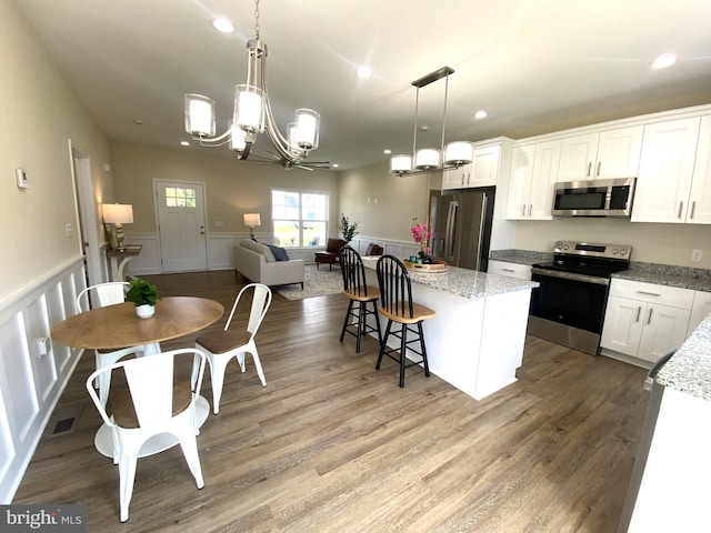 kitchen with white cabinets, a center island, stainless steel appliances, and hanging light fixtures