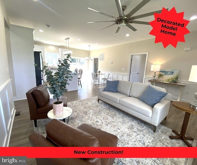 living room with ceiling fan with notable chandelier and hardwood / wood-style flooring