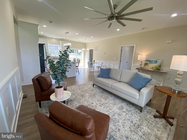 living room with ceiling fan with notable chandelier and wood-type flooring