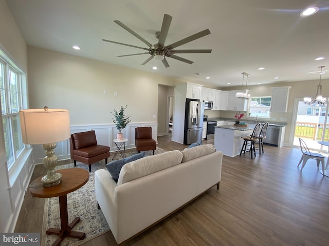 living room with ceiling fan with notable chandelier and hardwood / wood-style flooring