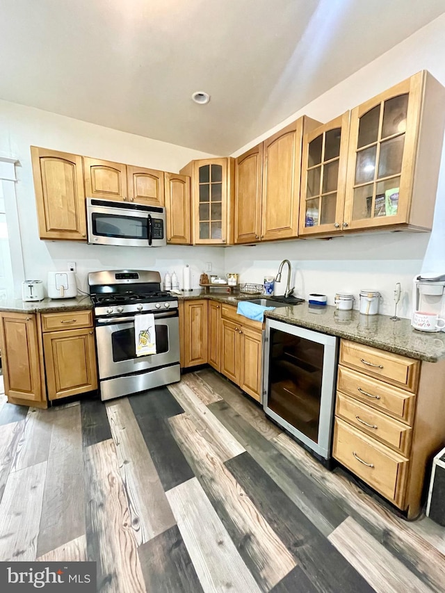 kitchen with sink, beverage cooler, dark wood-type flooring, stone countertops, and appliances with stainless steel finishes