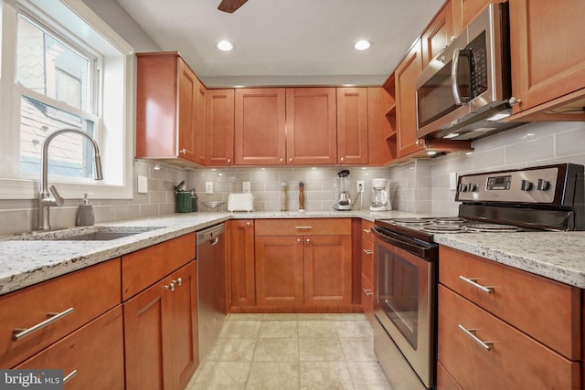 kitchen with light stone countertops, appliances with stainless steel finishes, backsplash, and sink