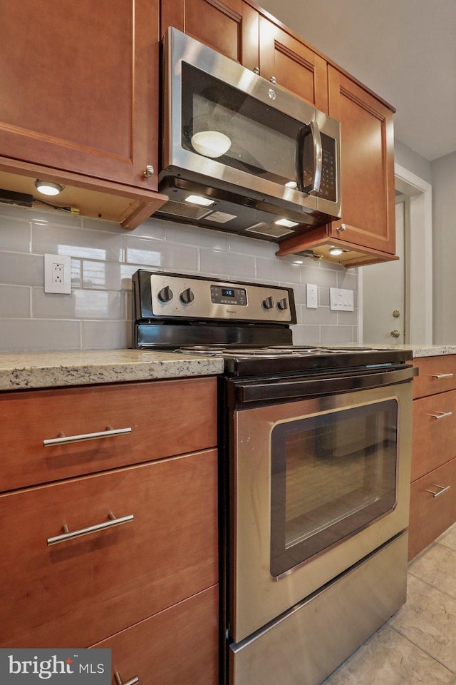 kitchen featuring light stone countertops, appliances with stainless steel finishes, tasteful backsplash, and light tile patterned floors