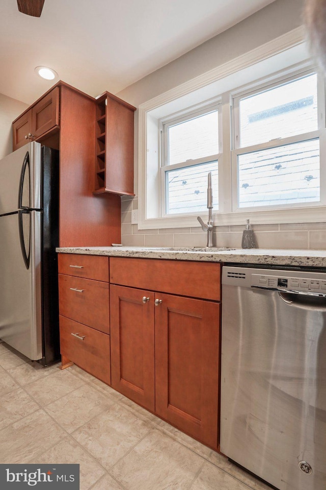 kitchen with decorative backsplash, appliances with stainless steel finishes, light stone counters, and sink