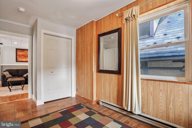 interior space with wooden walls and a baseboard heating unit