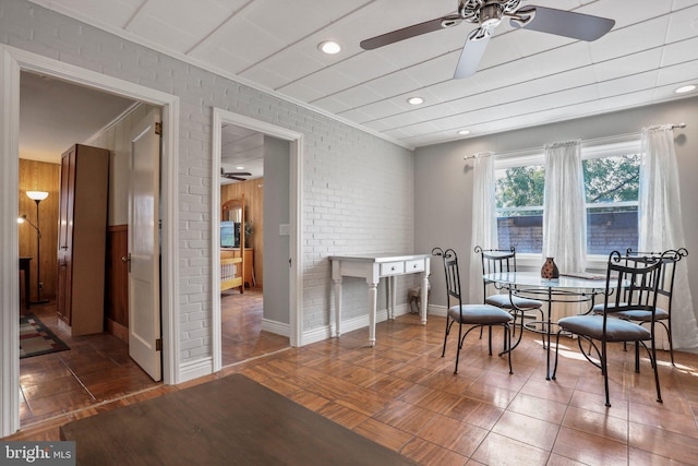 dining space with ceiling fan and brick wall