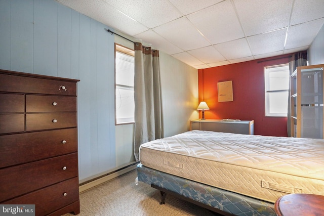 bedroom featuring a drop ceiling and multiple windows