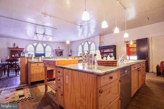 kitchen with decorative light fixtures, a center island with sink, stainless steel dishwasher, and sink