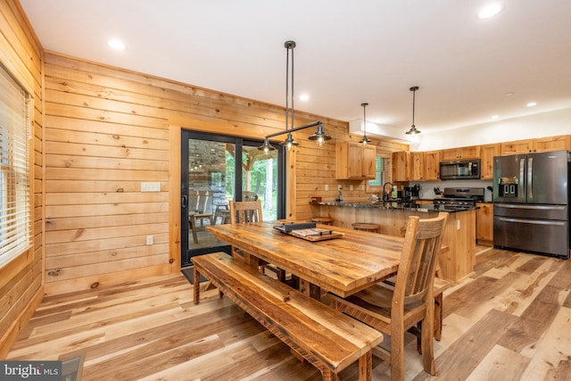 dining area featuring sink, light hardwood / wood-style flooring, and wood walls