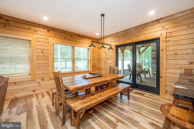 dining space featuring a wealth of natural light, wooden walls, and light hardwood / wood-style floors