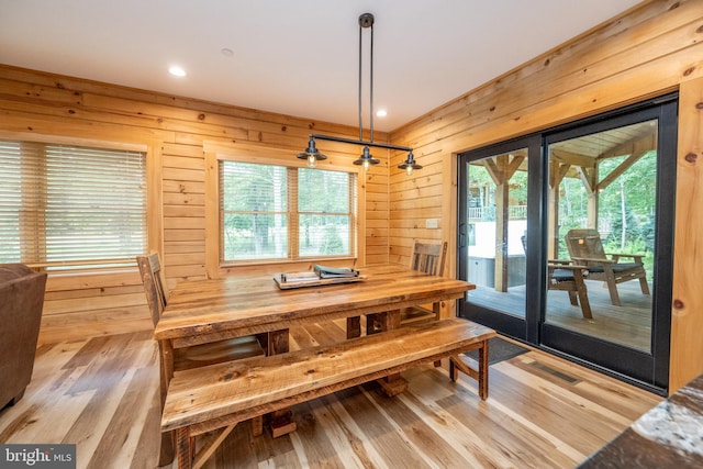 dining area with light wood-type flooring and wood walls