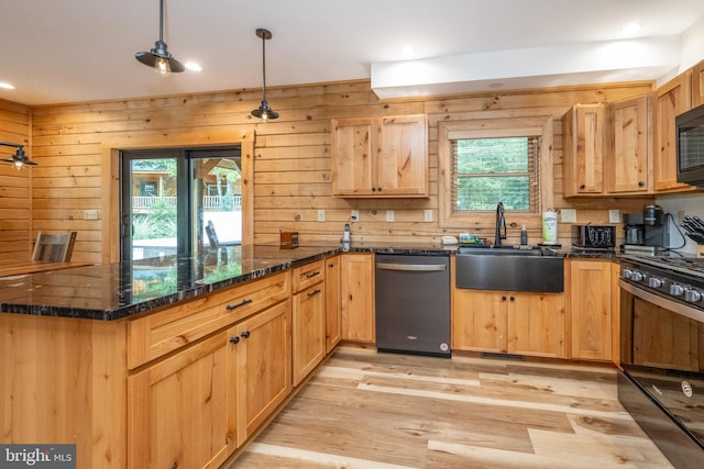 kitchen featuring light hardwood / wood-style flooring, hanging light fixtures, wood walls, and black appliances