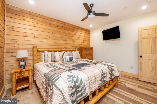 bedroom featuring ceiling fan, wood walls, and light wood-type flooring