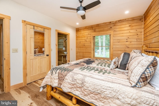 bedroom featuring wood walls, a closet, ceiling fan, and light wood-type flooring