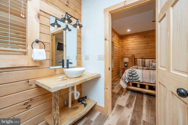 bathroom with wood walls, sink, hardwood / wood-style floors, and radiator heating unit