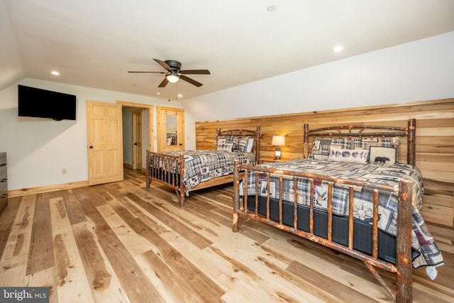 bedroom with hardwood / wood-style flooring, ceiling fan, wood walls, and vaulted ceiling