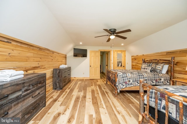 bedroom featuring light hardwood / wood-style floors, ceiling fan, lofted ceiling, and wood walls