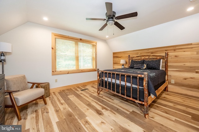 bedroom featuring hardwood / wood-style floors, vaulted ceiling, ceiling fan, and wood walls