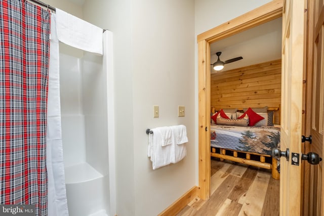 bathroom with ceiling fan, a shower with shower curtain, and hardwood / wood-style flooring