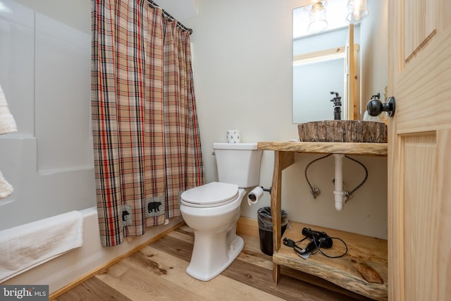 bathroom with wood-type flooring, toilet, and shower / bath combo