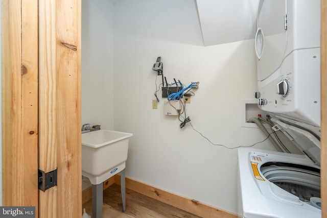 laundry room with hardwood / wood-style floors and stacked washer and clothes dryer