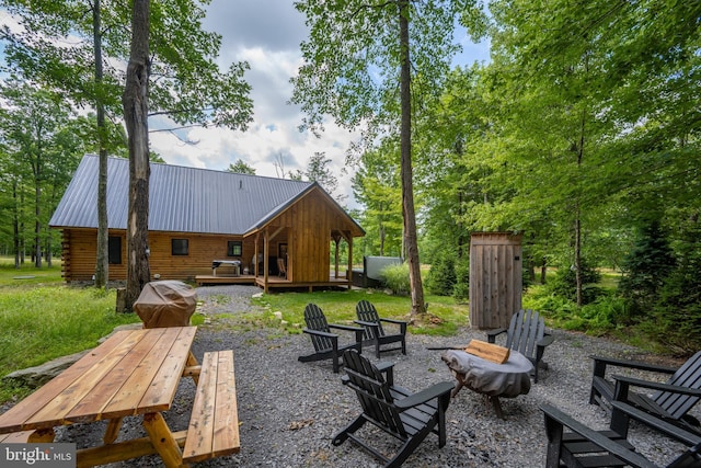 rear view of property with a wooden deck and an outdoor fire pit