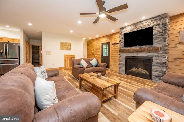 living room with wooden walls, a fireplace, and ceiling fan