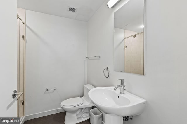 bathroom with tile patterned flooring, toilet, walk in shower, and sink