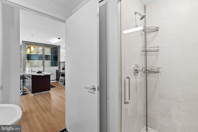 bathroom with hardwood / wood-style flooring and a shower with shower door