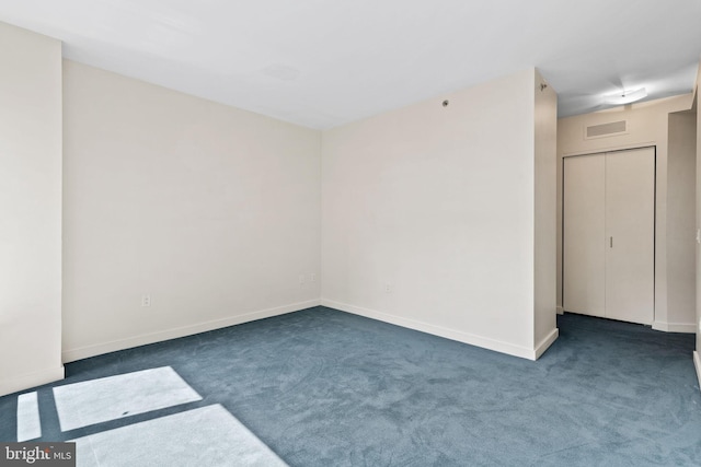 spare room featuring dark colored carpet