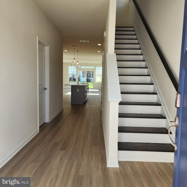 staircase with a chandelier, hardwood / wood-style floors, and sink