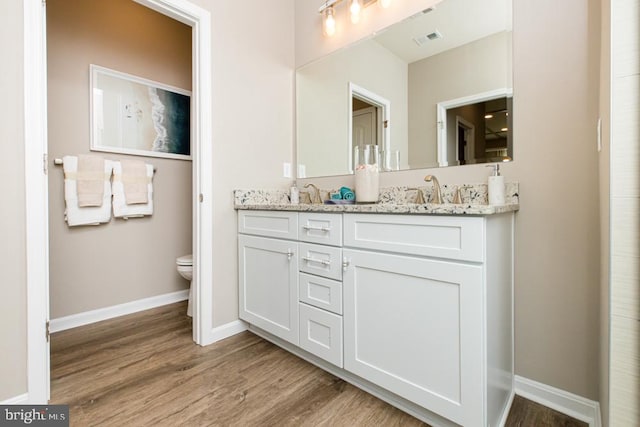 bathroom featuring toilet, hardwood / wood-style flooring, and vanity