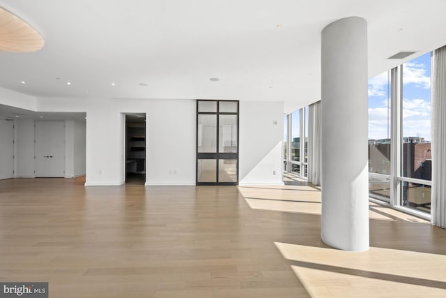 unfurnished living room featuring a wealth of natural light, expansive windows, and light hardwood / wood-style floors